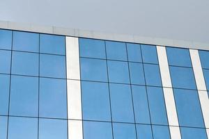 parede de prédio de escritórios de vidro azul com fundo de céu azul foto