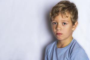 retrato de um menino triste em um fundo branco, uma criança frustrada foto