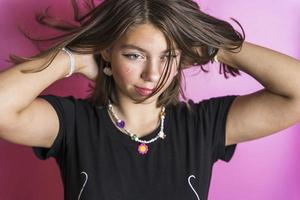 retrato de uma linda garota caucasiana balançando o cabelo, posando em um fundo rosa foto