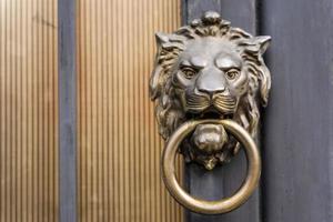 maçaneta da porta em forma de cabeça de leão com um anel na boca em uma porta de metal foto