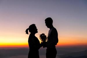 silhueta de casal de noivos apaixonados durante o nascer do sol com o fundo do céu da manhã. retratos pré-casamento imagens de casal feliz homem e mulher com céu natureza fundo. conceito de dia dos namorados. foto