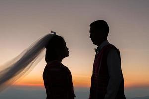 silhueta de casal de noivos apaixonados durante o nascer do sol com o fundo do céu da manhã. retratos pré-casamento imagens de casal feliz homem e mulher com céu natureza fundo. foto