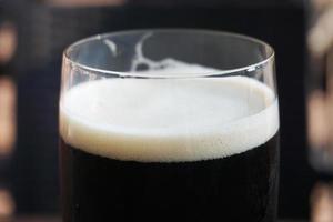 copo de cerveja escura, fundo desfocado foto
