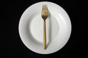 garfo de metal e prato em fundo preto foto