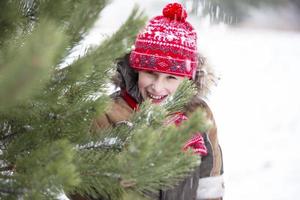 menino engraçado entre as árvores de natal cobertas de neve. criança no inverno. foto