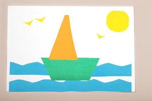 artesanato de papel para crianças. aplicação da criatividade das crianças. jardim de infância e escola de artesanato. sobre um fundo bege, um navio feito de papel colorido. foto
