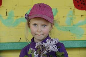 bielorrússia, cidade de gomil, 16 de maio de 2016. uma linda garotinha de chapéu segura um galho de lilases e sorrisos. foto