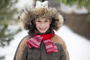 menino engraçado entre as árvores de natal cobertas de neve. criança no inverno. foto