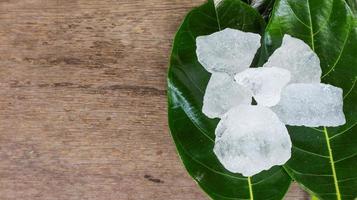 cubos de alume cristalino ou alume de potássio em folhas verdes conceito de substância química composta para spa de beleza e tratamento industrial de axilas foto