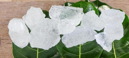 cubos de alume cristalino ou alume de potássio em folhas verdes conceito de substância química composta para spa de beleza e tratamento industrial de axilas foto