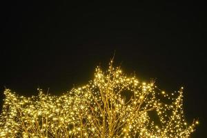 árvore com luzes brilhantes em um mercado de natal com céu negro ao fundo foto