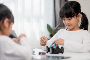 os alunos da ásia aprendem em casa na codificação de carros robóticos e cabos de placa eletrônica em haste, vapor, código de computador de tecnologia de ciência de engenharia matemática em robótica para o conceito de crianças. foto