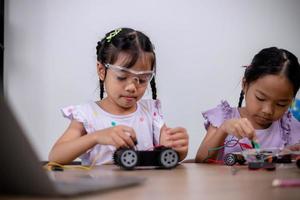 estudantes asiáticos aprendem em casa codificando carros robôs e cabos de placas eletrônicas em haste, vapor, matemática engenharia ciência tecnologia código de computador em robótica para conceitos infantis. foto