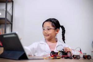 estudantes asiáticos aprendem em casa codificando carros robôs e cabos de placas eletrônicas em haste, vapor, matemática engenharia ciência tecnologia código de computador em robótica para conceitos infantis. foto