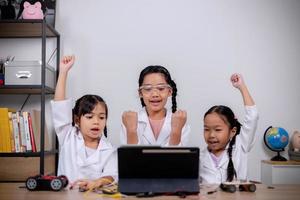 estudantes asiáticos aprendem em casa codificando carros robôs e cabos de placas eletrônicas em haste, vapor, matemática engenharia ciência tecnologia código de computador em robótica para conceitos infantis. foto