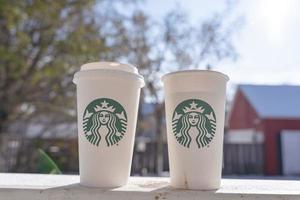 marinette, wi, eua - 14 de novembro de 2023- xícaras de café quente starbucks colocadas na neve branca no jardim de inverno, bebida fresca e quente para levar conceito. starbucks cafe coffee shop. foto