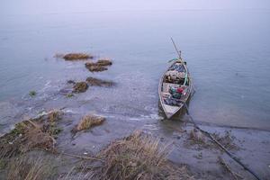 paisagem de um barco de madeira na margem do rio padma em bangladesh foto