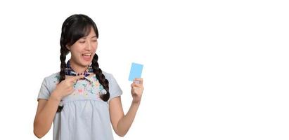 retrato de uma bela jovem asiática feliz em vestido jeans segurando cartão de crédito em fundo branco foto