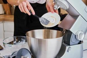 mulher cozinhando na cozinha e usando máquina de cozinha foto