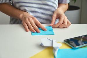 conceito de bricolage. mulher faz coelho de páscoa de origami de papel colorido. aulas de origami foto