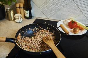 mulher cozinhando molho à bolonhesa na cozinha foto