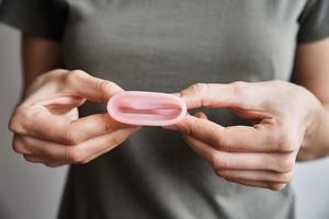 mulher segura copo menstrual nas mãos foto