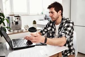 homem trabalha em home office com laptop e documentos foto