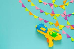 pistola de água com bandeira de festa colorida para celebração do festival songkran em fundo de cor azul. conceito mínimo de férias. foto