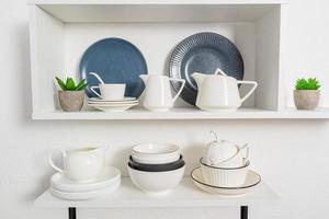 vista de primeiro plano, close-up de prateleiras de cozinha aberta com utensílios de porcelana e cerâmica. fundo de cozinha elegante em tons de branco. foto