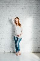 menina grávida ruiva em uma blusa leve e jeans azul foto