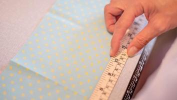 mãos femininas de designer no trabalho com close-up de tecido. alfaiate medindo a quantidade necessária de material para costurar pano.
