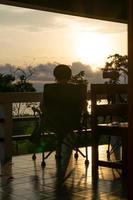 a pessoa das mulheres da silhueta relaxa sozinha em uma cadeira e desfruta da natureza tropical pela manhã com a hora do café, férias de férias, conceito de liberdade de vida. foto