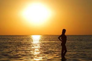 silhueta da jovem em uma baía de mar em um pôr do sol foto