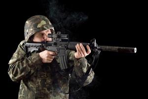 soldado alertado mantendo uma arma fumegante foto