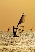 silhuetas de um windsurfista nas ondas de um golfo foto