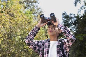 meninos asiáticos usando binóculos para observar pássaros em árvores e pescar no rio no parque nacional local durante o acampamento de verão, ideia para aprender criaturas e animais selvagens e insetos fora da sala de aula. foto