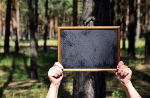 mãos humanas segurando uma moldura de madeira vazia com fundo preto foto