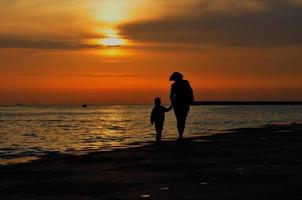 mulher com criança de mãos dadas corre ao longo do passeio marítimo foto