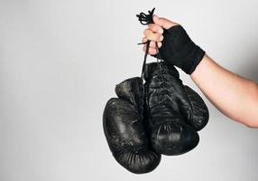 braço masculino envolto em uma bandagem esportiva elástica preta segura luvas de boxe de couro vintage velhas foto