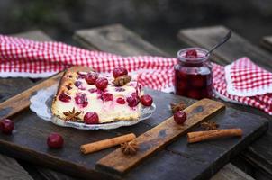 pedaço de bolo de queijo cottage e bagas de cereja em um prato de vidro foto