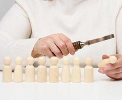 mulher segurando uma lupa e homens de madeira em uma mesa branca. conceito de recrutamento de pessoal, funcionários talentosos foto