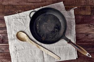 frigideira preta vazia em uma superfície de madeira marrom foto