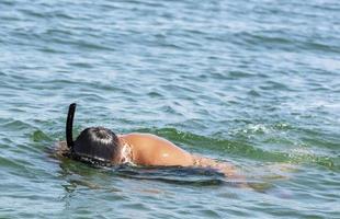 homem mergulhador com um tubo flutuando na superfície da água foto
