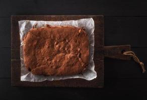 torta de brownie assada inteira quadrada em uma placa de madeira marrom foto