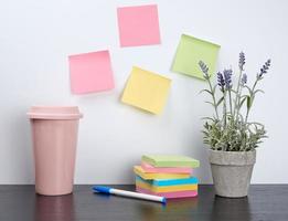 pilha de cadernos em espiral e adesivos coloridos, ao lado de um vaso de cerâmica com uma flor foto