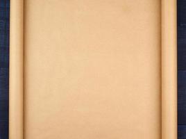 rolo não torcido de papel artesanal marrom em um fundo azul de madeira, espaço vazio foto