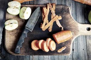cortar cenouras e maçã verde fatiada em uma placa de cozinha foto