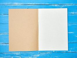 abra o caderno escolar verificado no fundo azul de madeira foto
