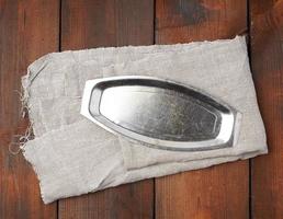 prato vazio de ferro em um guardanapo têxtil cinza, fundo de madeira marrom, vista superior foto