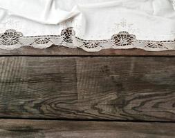 toalha de renda têxtil de cozinha branca dobrada sobre uma mesa de madeira cinza de tábuas antigas foto